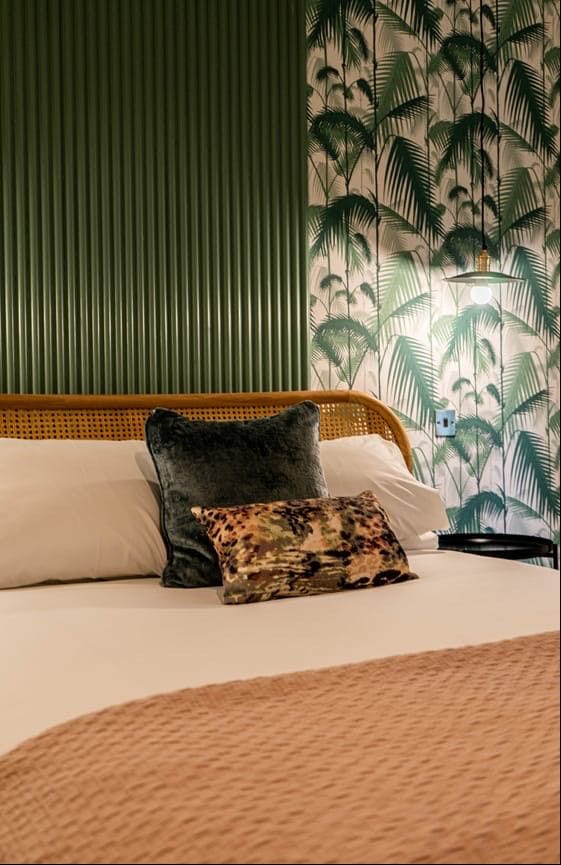Jacobean Hotel rattan headboard, velvet cushions and palm wallpaper