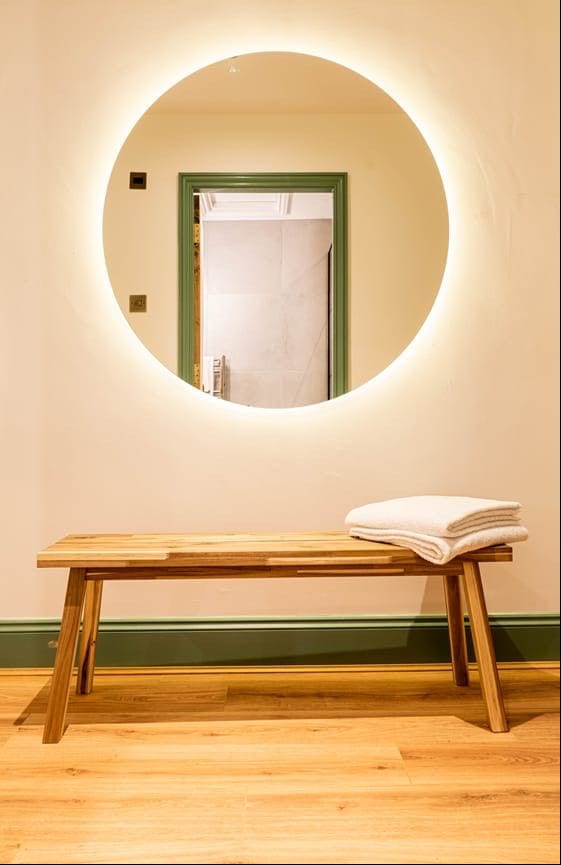 Jacobean Hotel backlit round mirror above an oak bench