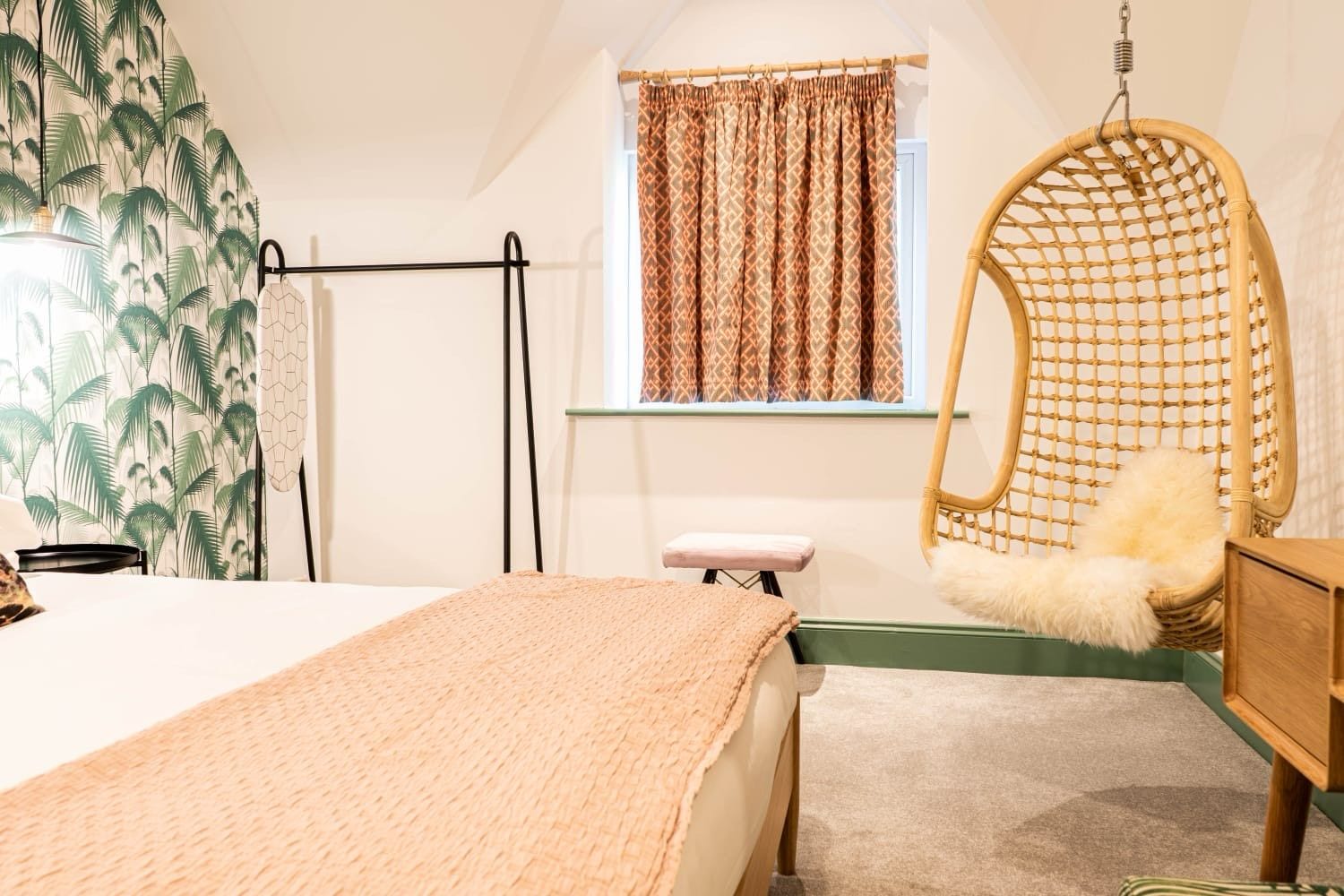 Jacobean Hotel bedroom with clothes rail, patterned curtains and hanging chair