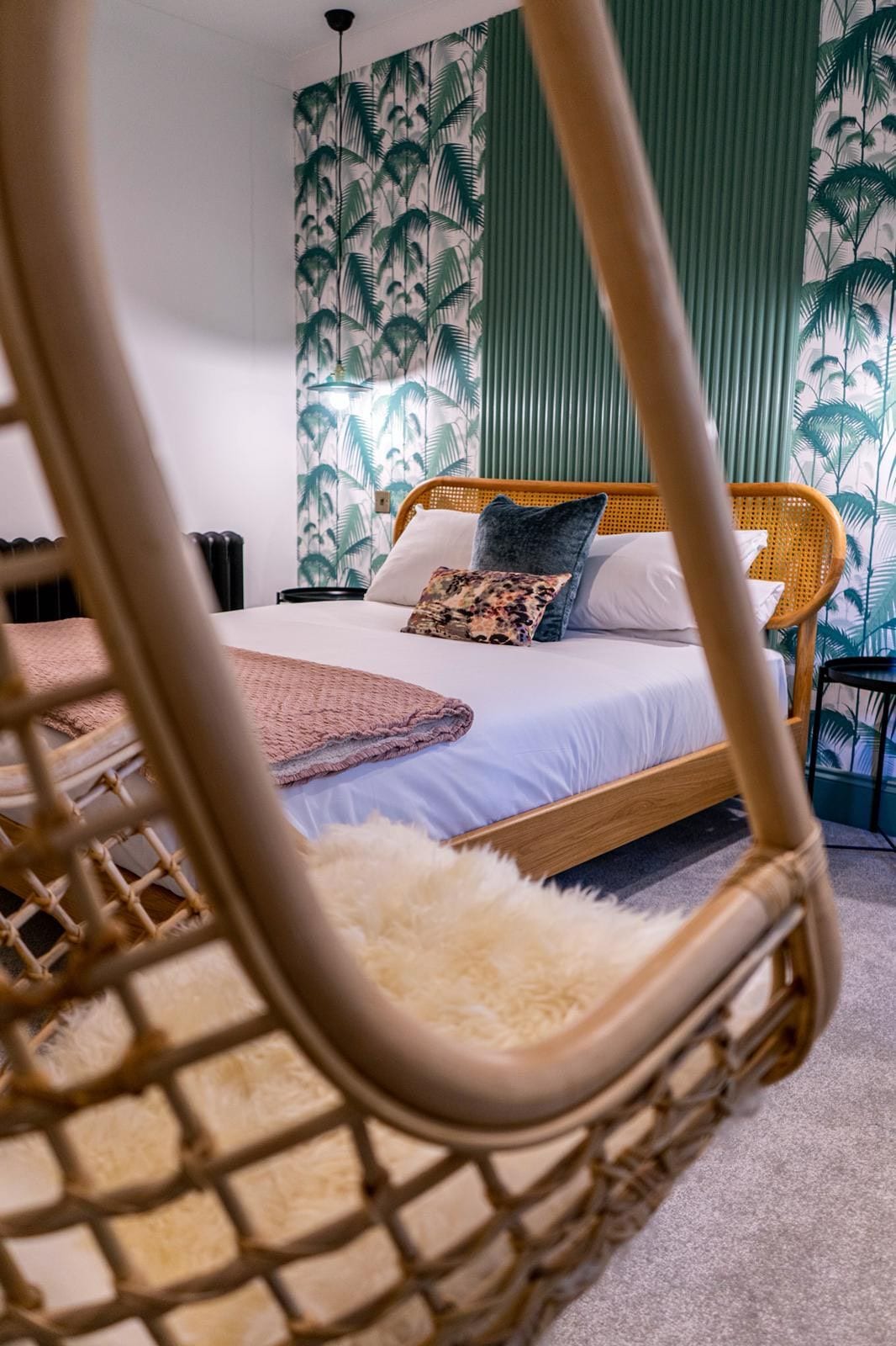 Jacobean Hotel bed seen through the hanging rattan chair