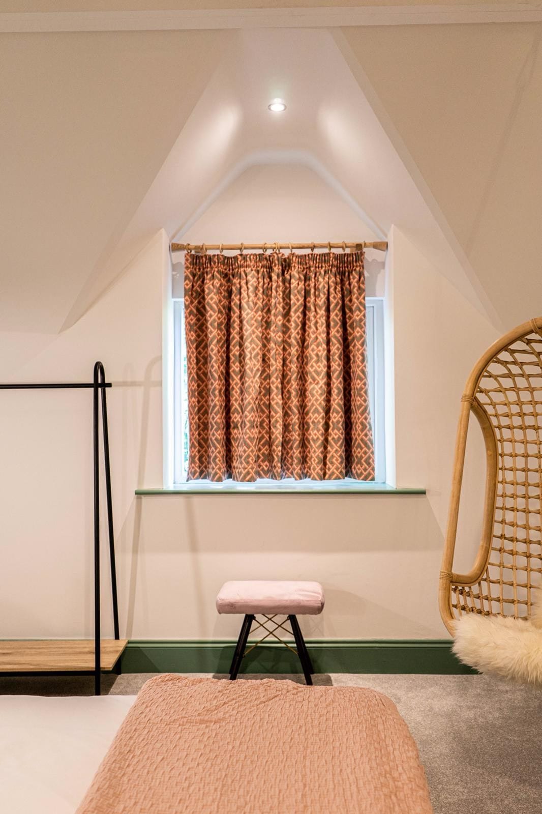 Jacobean Hotel attic window with patterned curtains and pink stool